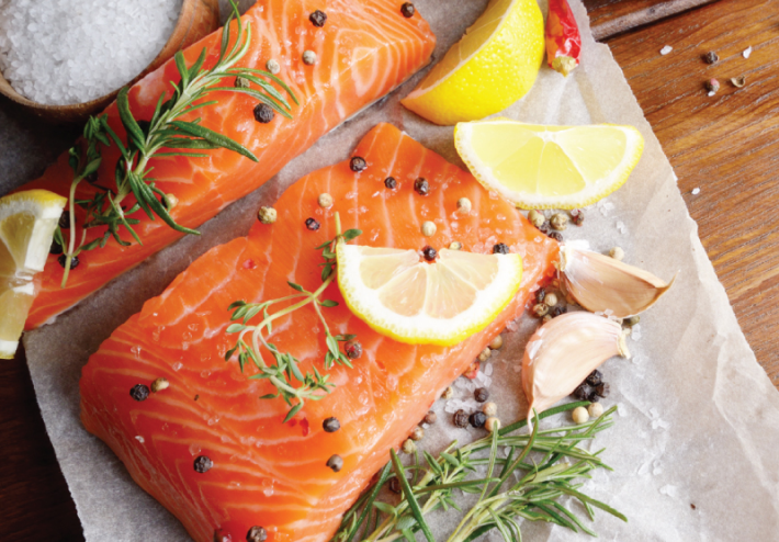 One of the lifestyle pictures used in the brand guide and on the website. Shows fresh salmon filets with seasonings like salt, pepper, herbs and lemon wedges - ready to cook.